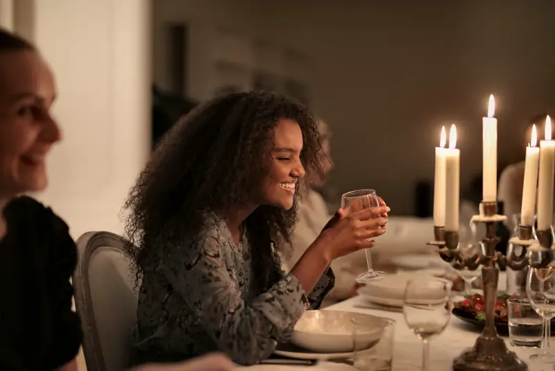A guest laughing with a wine glass in hand beside a silver candelabra at dinner