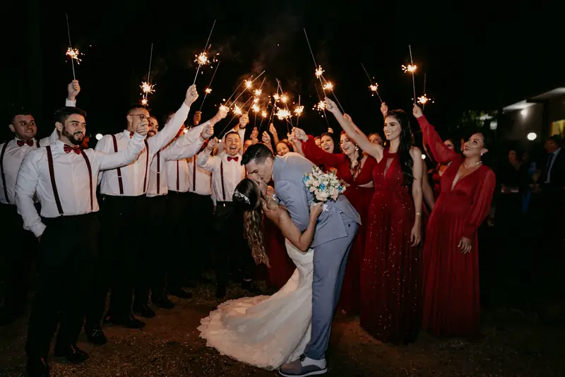 The groom dips the bride for a kiss inside a tunnel of guests holding sparklers